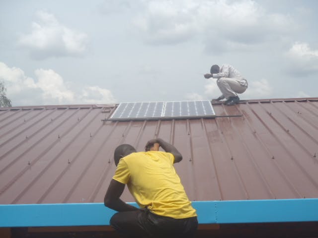 Men installing solar panel on school roof