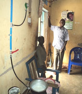 Peter at his home with bio gas system Gas tubes connected to stove, with a pot cooking on the stove