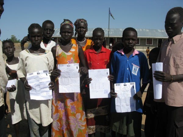 2010 students in Ulang displaying their report cards