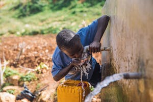 Boy drinks clean water from faucet in Haiti