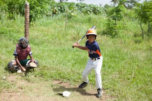 Children play baseball at a sports equipment distribution in the DR.