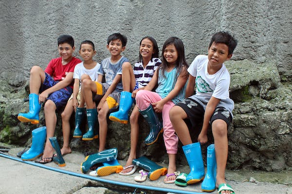 Kids in the Philippines smiling with rubber boots from Food for the Hungry.