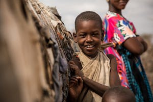 Young boy in Kenya smiles for the camera.