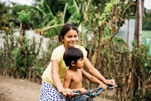 Girl in Nicaragua rides bike with young boy. Food for the Hungry.