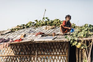 Rohingya refugee boy sits on top of roof in Cox's Bazar.