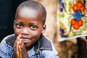Young Rwandan boy in Food for the Hungry's work area folds his hands in prayer