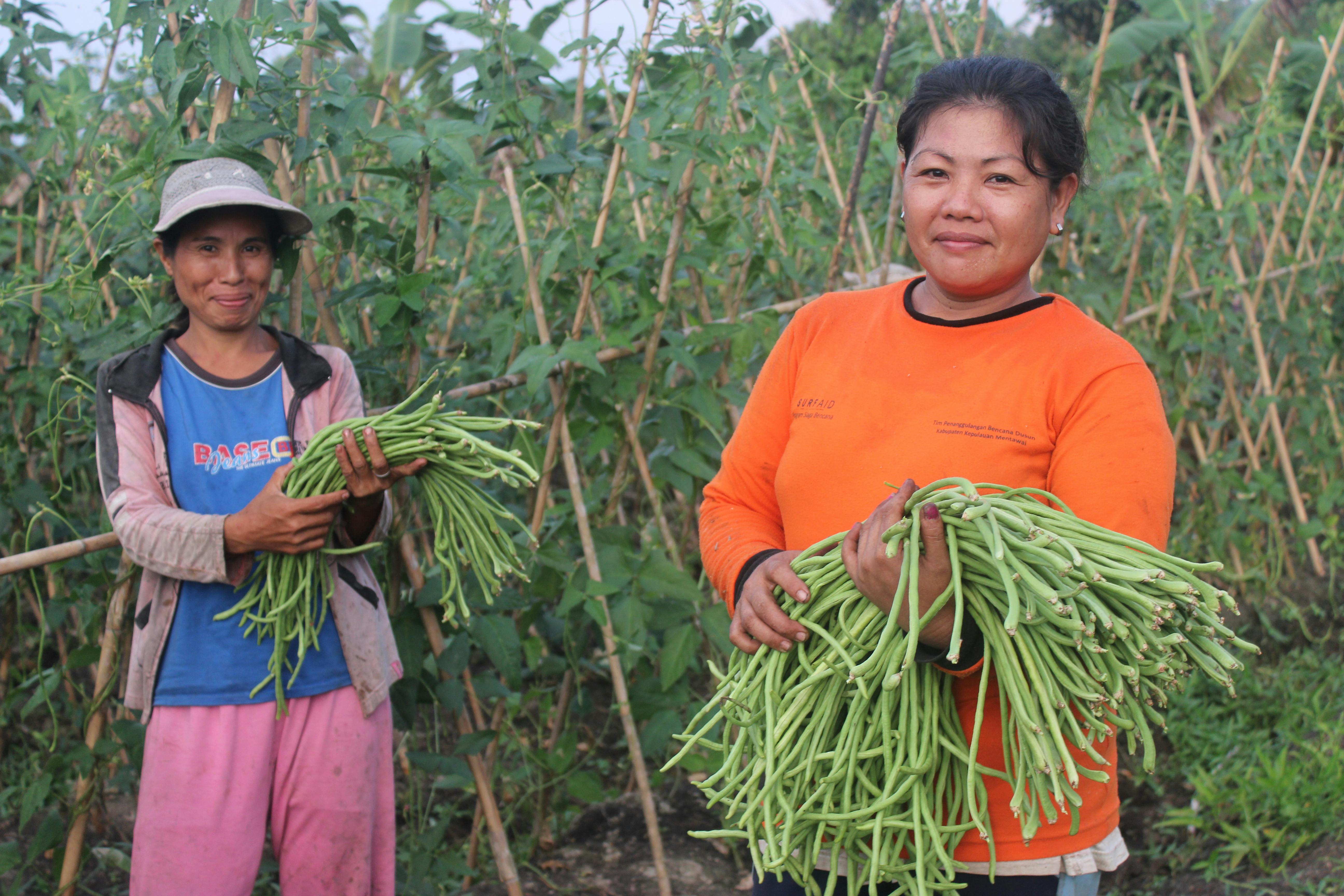 International Womens Day Photoessay - Two women in Philippines stand with their vegetables in the field
