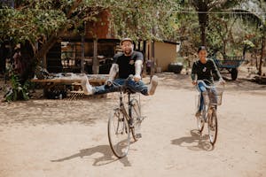 Child sponsor Doug Penick and sponsored child, Sopheap, ride bikes together in Cambodia.