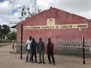Four men in front of red cement school building