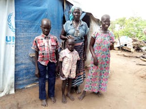 Cecilia, a South Sudanese refugee, poses with her three grandchildren outside an FH and UNHCR tent.