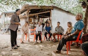 Village members in Cambodia meet under a tree in a circle