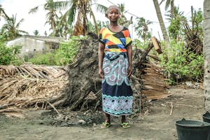 Woman in colorful dress stands in front of her house after Cyclone Idai struck Beira, Mozambique.