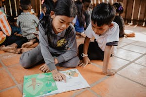 Two kids in Cambodia read a picture book