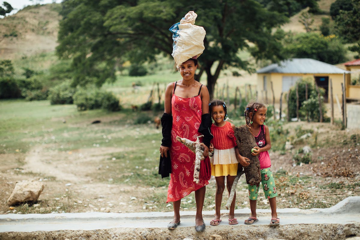 A woman with a bag on her head, and two children next to her in the Dominican Republic