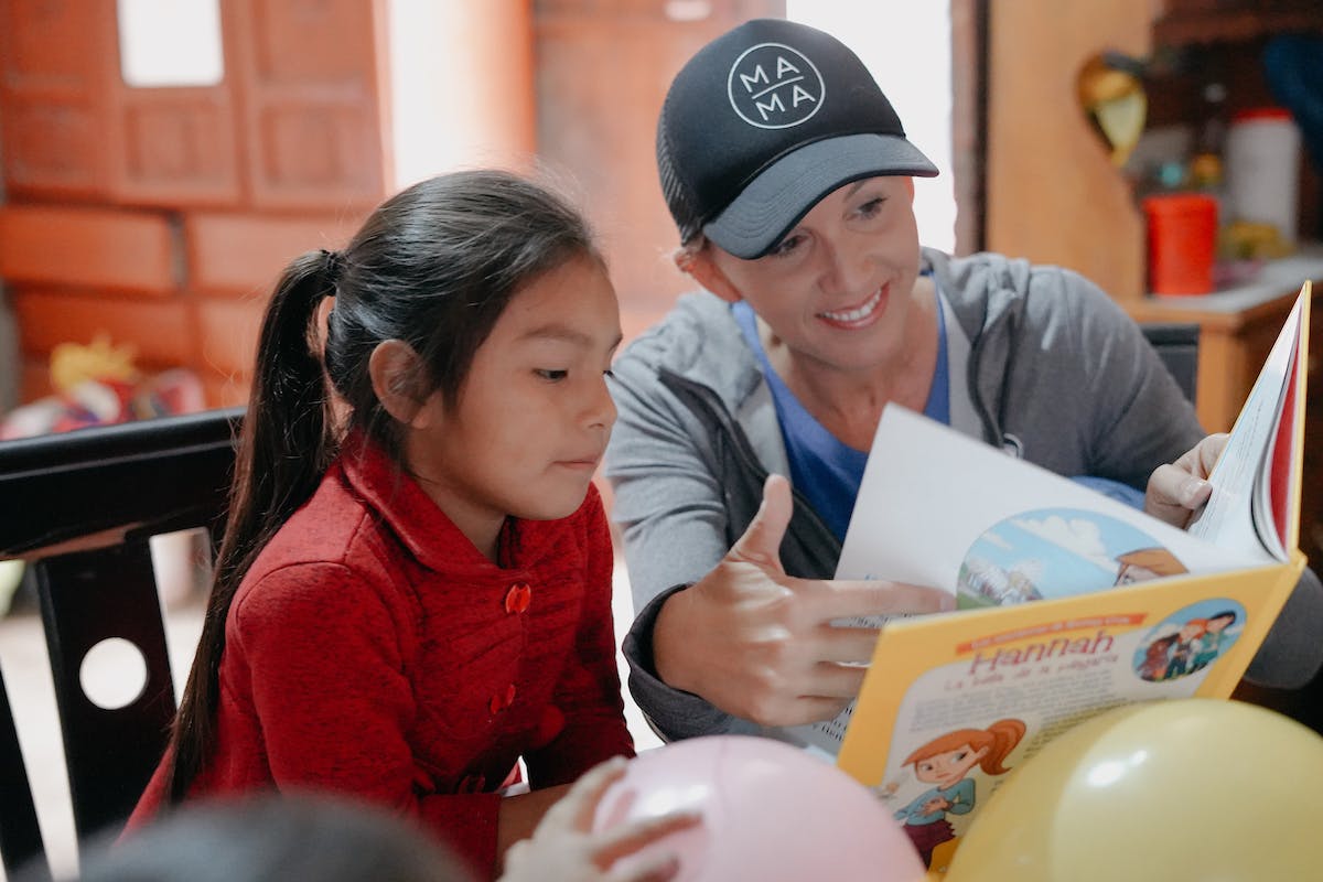 Erin Weidemann of Truth Becomes Her shares a Bible Belles book with her sponsored child, Evelyn, on her recent trip to Peru.