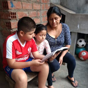 Youth in Peru receive Bibles. Juan sits with his sister and mother reading the Bible