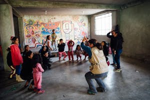 Children in Peru stand in a classroom, playing games in a circle to improve their social emotional skills as part of an early childhood learning program.