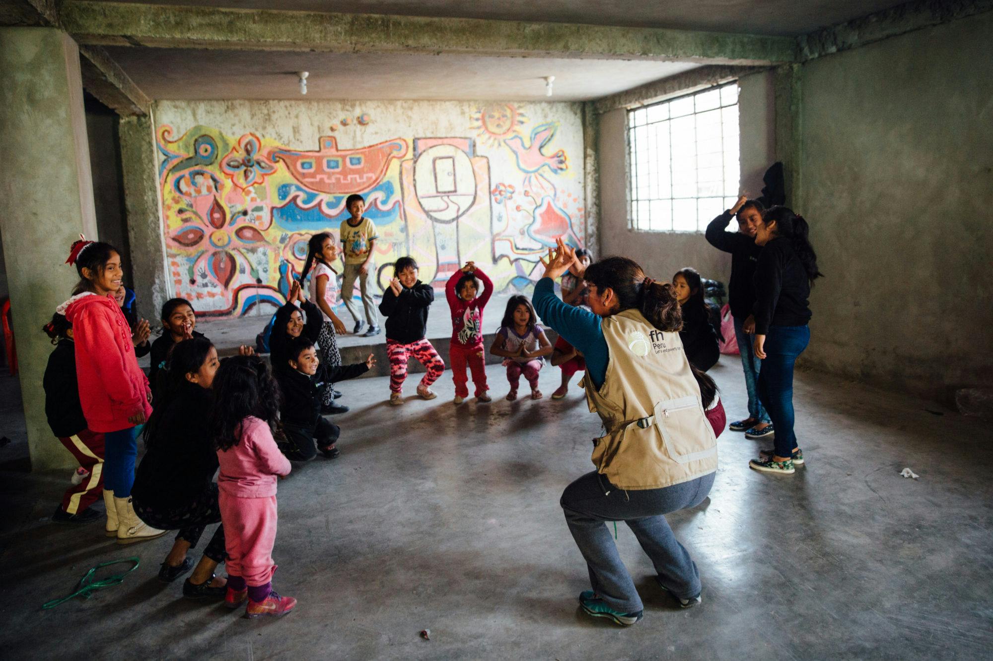Children in Peru stand in a classroom, playing games in a circle to improve their social emotional skills as part of an early childhood learning program.