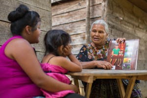 woman in traditional guatemalan dress teaching hygiene to mother and child