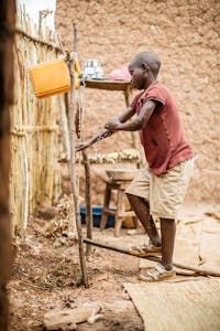Burundian boy washing hands with tippy tap