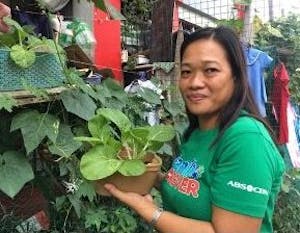 woman in green shirt showing off vegetable garden