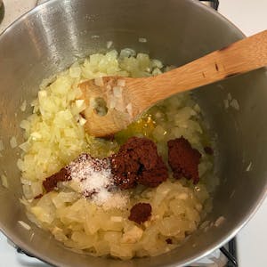 cooked onions in a pot being mixed with salt and berbere paste