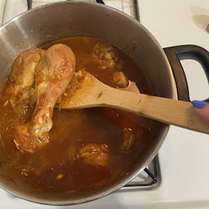 a pot of doro wat on the stove, chicken being added