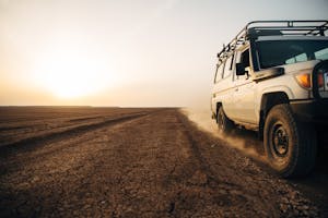 Jeep driving on dusty road with horizon in the background
