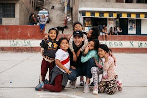 Peruvian children give a big hug to a visitor on a concrete soccer field in the cerros of Lima