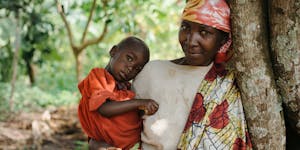 Burundi mother holds baby under a tree