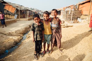 Three boys on a dirt path in a refugee camp