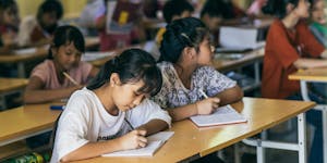 Two girls in Vietnam studying at their desks in a classroom