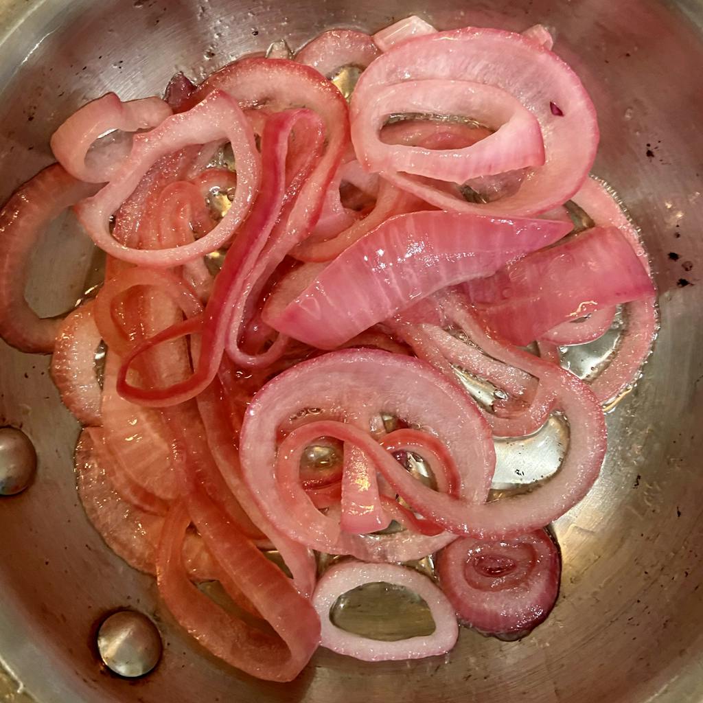 red onions frying in a pan