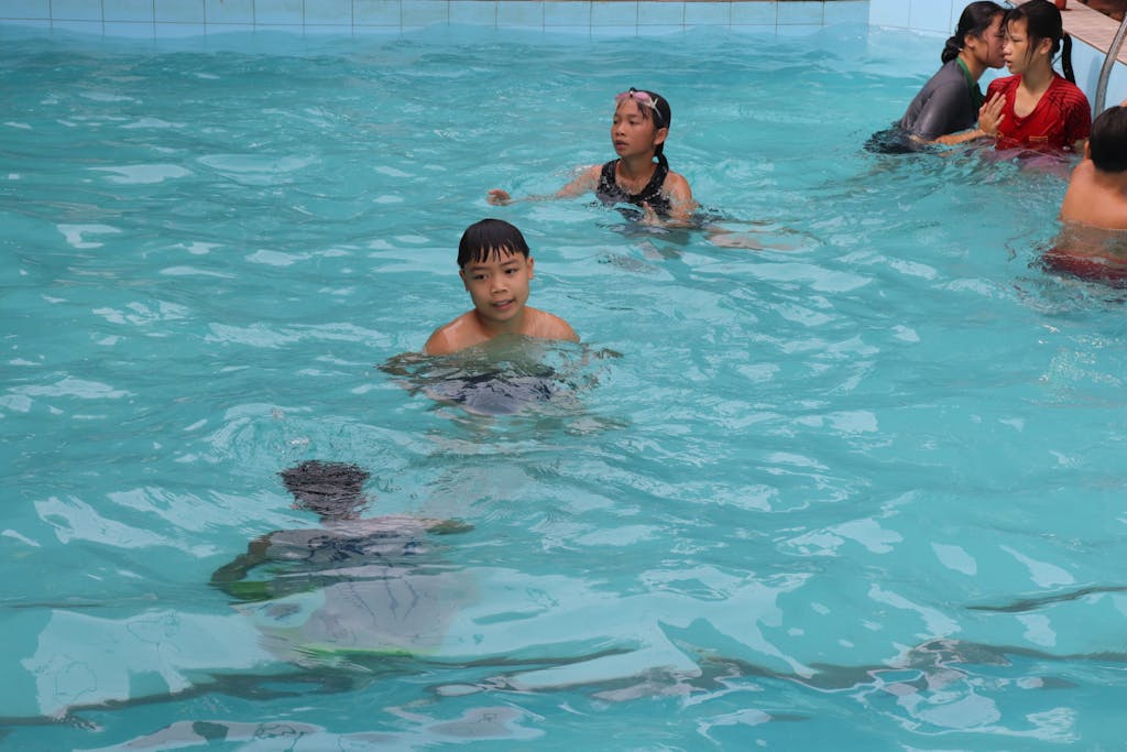 Children in swimming pool with boy looking at camera