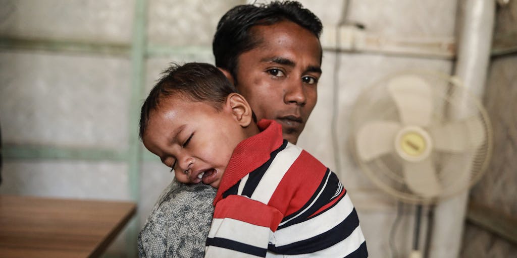 Rohingya Man holding small toddler.