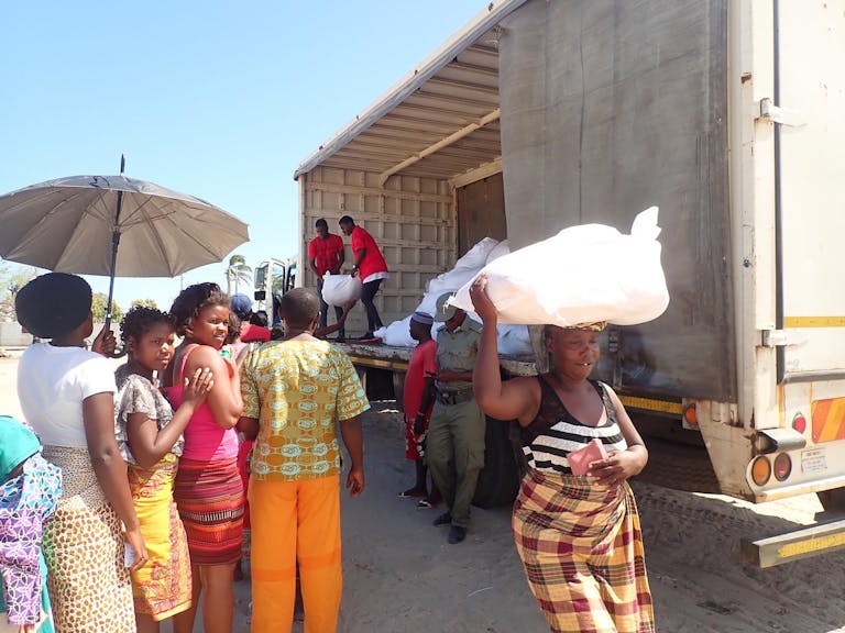 people receiving sacks of food from truck