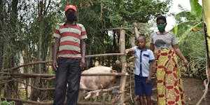 Family from Rwanda standing in front of their pig pen
