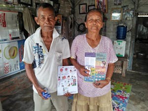 Elderly couple holding their COVID-19 education flyers