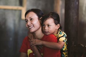 Vietnamese woman smiling with young child hugging her