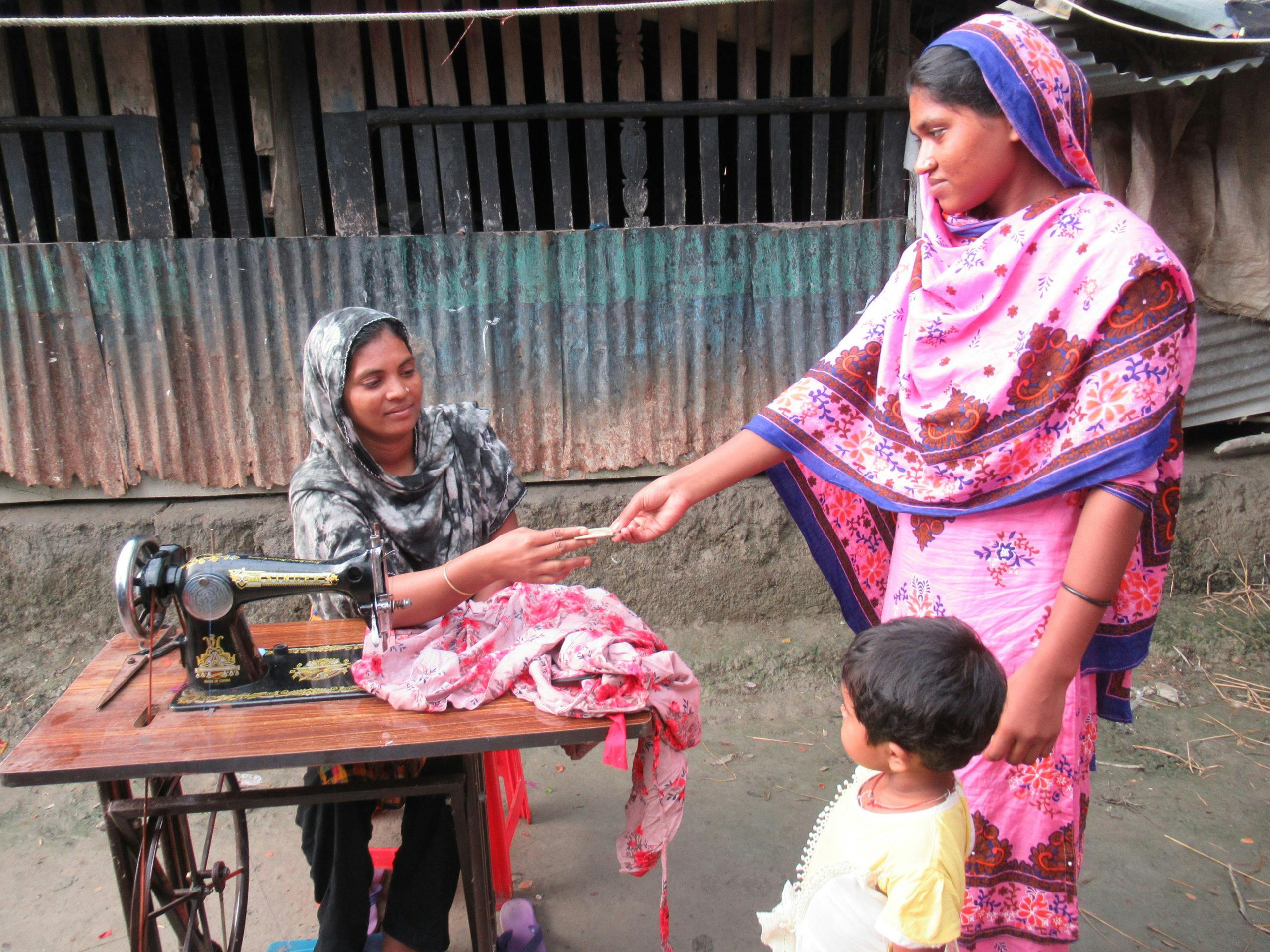 Mustakin's mother using the FH provided sewing machine to generate income.