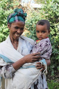 Ethoipian mother smiling and holding 18 month old baby