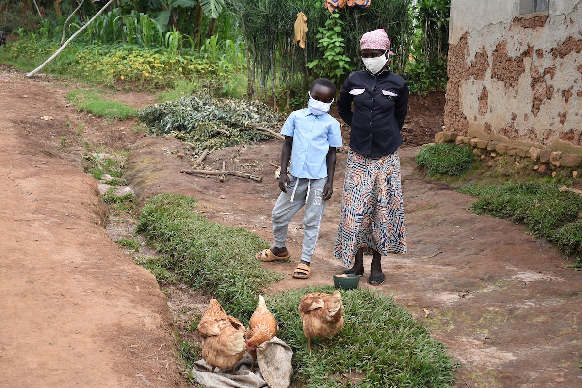 Mother and child standing together next to their chickens.