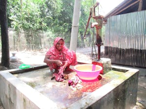 Nargis Begum, mother of two, washes laundry in clean water provided by the tube well FH installed near her home.