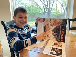 smiling boy in sweater at desk looking at FH gift catalog