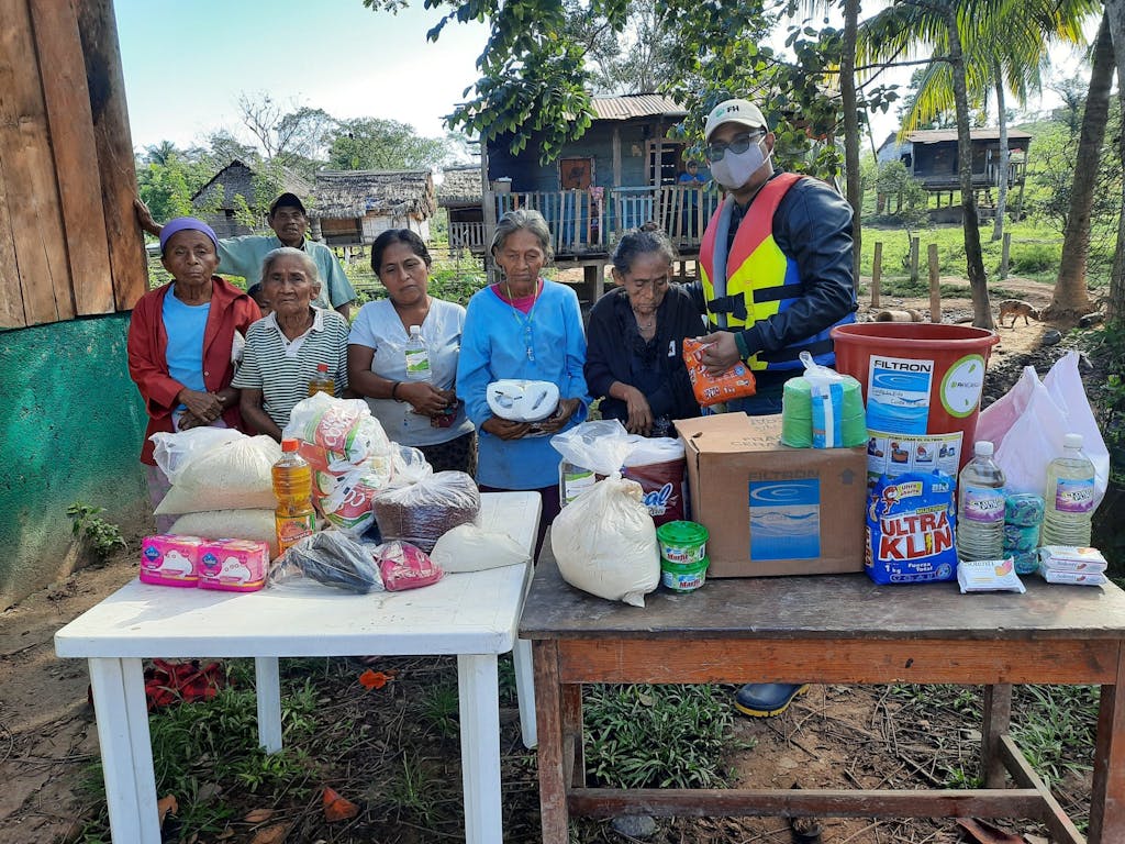 group of people behind tables filled with relief food and cleaning supplies