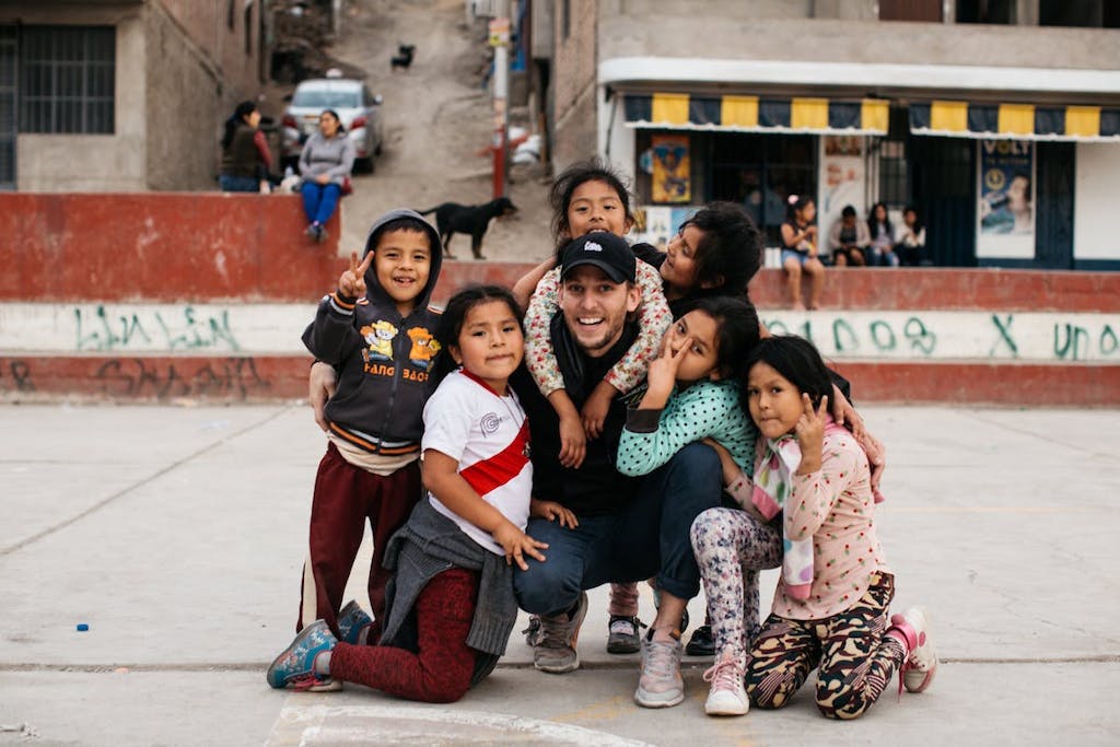 Peruvian children give a big hug to a visitor on a concrete soccer field in the cerros of Lima