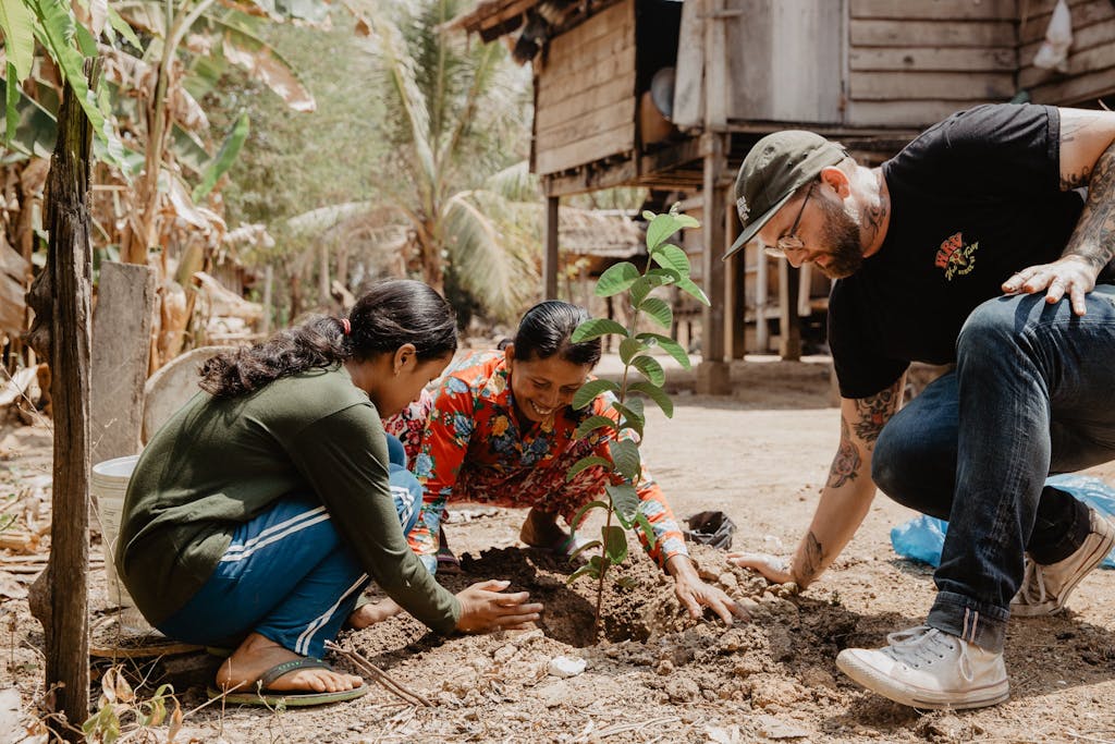 FH staffer Doug Penick plants tree with sponsored child, Sopheap, and her mother.