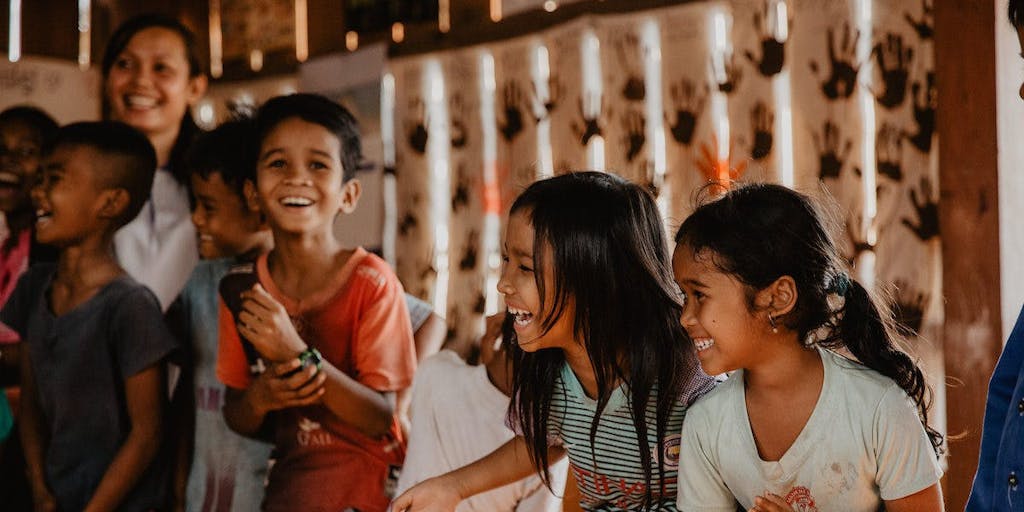 Girls in Cambodia laugh as they play a game with peers
