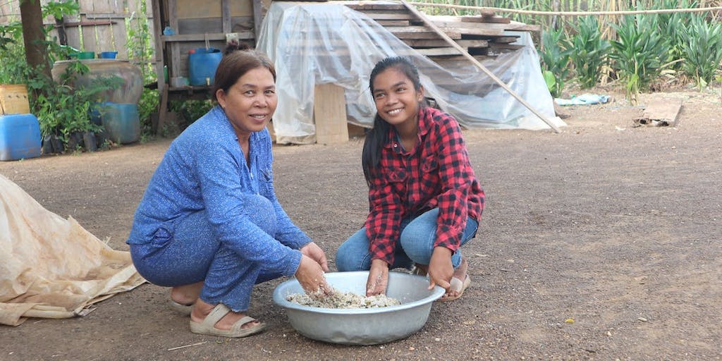 woman and child preparing chicken feed