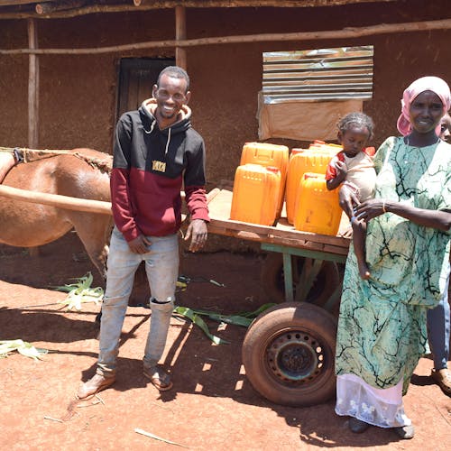 Aliyi and his family display the cart and water jugs it allows him to transport.